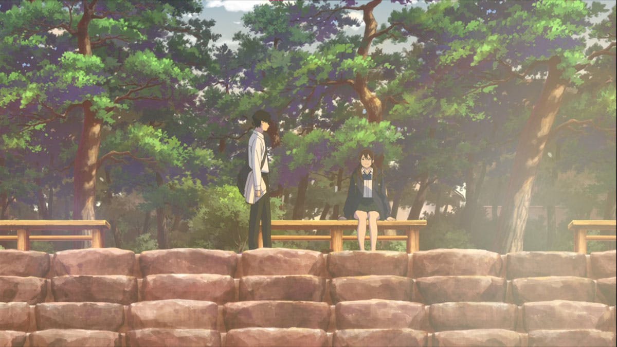 In a poignant scene from the movie 'I Want to Eat Your Pancreas,' two characters sit closely on a wooden bench embraced by the serenity of a lush forest, engrossed in a heartfelt conversation that speaks volumes about their deep connection and shared moments of vulnerability and introspection.